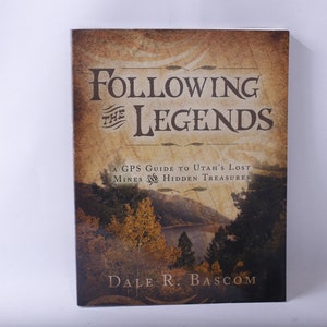 May include: A book cover with a brown background and a picture of a lake and trees. The title is "Following the Legends" and the subtitle is "A GPS Guide to Utah's Lost Mines & Hidden Treasures". The author's name is "Dale R. Bascom".
