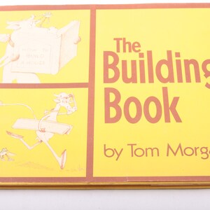 Puede incluir: La portada de un libro amarillo titulado "The Building Book" de Tom Morgan. La portada presenta ilustraciones de un animal de dibujos animados que lleva un libro y una tabla de madera.