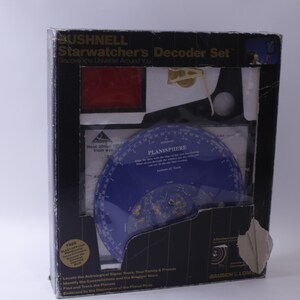 May include: A black box with the text "Starwatcher's Decoder Set" and "Discover the Universe Around You!" on the front. The box contains a blue planisphere with gold stars and the text "Planisphere" on it.