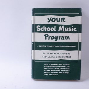 May include: A green book with white stripes titled "YOUR School Music Program: A Guide to Effective Curriculum Development" by Frances M. Andrews and Clara E. Cockerille. The book cover also includes information on how to organise and manage music education programmes for all grades.