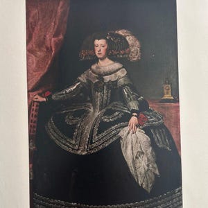 May include: A portrait of a woman in a dark dress with a wide skirt and elaborate trim. She wears a large, ornate hat with feathers and holds a white cloth. The background features a red curtain and a small clock.