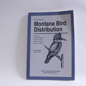 Puede incluir: Una cubierta de libro azul con el título "Montana Bird Distribution" de P.D. Skaar. La cubierta presenta una ilustración en blanco y negro de un pájaro posado en una rama.