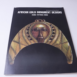 Peut inclure: Couverture de livre avec le titre "African Gold Ornament Designs" par Diane Victoria Horn. La couverture présente une illustration dorée et noire d'une coiffe africaine traditionnelle.