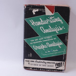 Op de afbeelding: Een zwart en groen boek getiteld "Handwriting Analysis: The Art and Science of Reading Character by Grapho Analysis" door M. Bunk. De boekomslag heeft een witte sticker met de tekst "Your Own Handwriting Analyzed FREE! See Back of This Jacket."