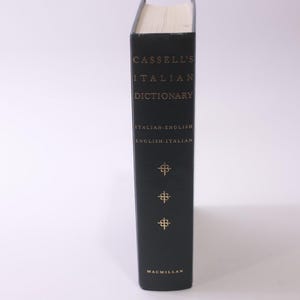 May include: A hardcover book titled "Cassell's Italian Dictionary" with gold lettering on a black cover. The spine includes the text "Italian-English, English-Italian" and decorative gold symbols. The publisher is Macmillan.