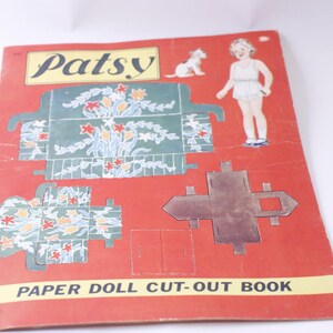 Peut inclure: Un livre de découpage de poupée en papier vintage mettant en scène Patsy. La couverture est rouge avec un titre blanc et une illustration en noir et blanc d'une fille et d'un chien. Le livre comprend une poupée en papier, des vêtements et des meubles.