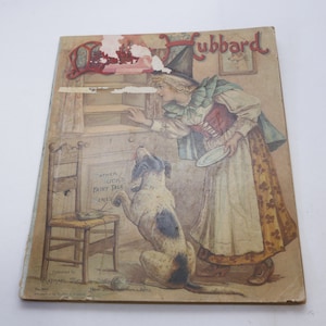 Puede incluir: Una portada de libro vintage con una mujer con un sombrero de bruja y un vestido, sosteniendo un plato. Un perro está de pie sobre sus patas traseras, mirando a la mujer. El título del libro es "Mother Goose's Fairy Tale Chimes".