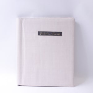 May include: A white photo album with a black label that reads "Photo Album" in gold lettering.