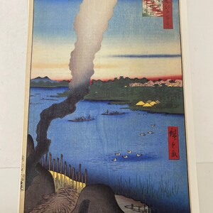 May include: A Japanese woodblock print depicting a scenic landscape with a large plume of smoke rising from a body of water. The print is titled "Sumida River" in Japanese characters. The print features a blue sky, a river, and a mountain in the distance. The print is in a traditional Japanese style.