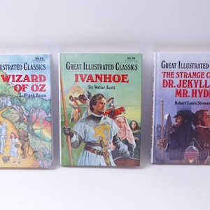 May include: Three paperback books with colorful covers featuring illustrations from classic novels. The titles are "The Wizard of Oz", "Ivanhoe", and "The Strange Case of Dr. Jekyll and Mr. Hyde".