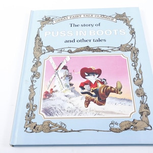 May include: A light blue children's book titled "The story of Puss in Boots and other tales." The cover features an illustration of a cat in boots, a windmill, and a decorative border. The book is a classic fairy tale.