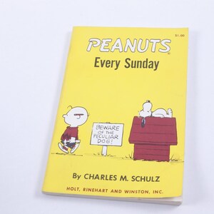May include: A yellow paperback book with the title "PEANUTS Every Sunday" and a cartoon image of Charlie Brown and Snoopy. The book is by Charles M. Schulz and published by Holt, Rinehart and Winston, Inc.
