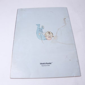 Pu&ograve; includere: Un libro tascabile vintage con una copertina azzurra che presenta un'illustrazione di un bambino in una tutina blu. Il testo "Weekly Reader Paperback Clubs" &egrave; stampato in basso sulla copertina.