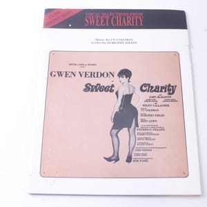 May include: A vintage program for the musical "Sweet Charity" starring Gwen Verdon. The cover features a black and white photo of Gwen Verdon in character, with the title of the musical in large, bold letters.