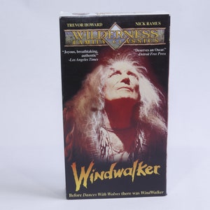 Puede incluir: Una caja de cinta VHS para la película Windwalker, con un retrato de un hombre con cabello largo y blanco sobre un fondo oscuro. El texto en la caja dice "Wilderness Family Classics" y "Before Dances With Wolves there was WindWalker".