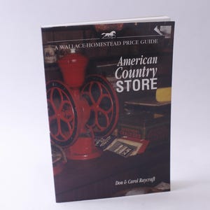 May include: A Wallace-Homestead Price Guide book titled "American Country Store" featuring a red antique coffee grinder with a black and white patterned design. The book cover also features a vintage store interior with various items.