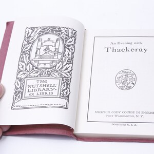 May include: An open book with a red cover. The front cover features a black and white illustration of a printing press with the text "The Nutshell Library - Ex Libris". The back cover features the text "An Evening with Thackeray", a black and white illustration of a seal, and the text "Sherwin Cody Course in English, Port Washington, N. Y. Made in the U.S.A."