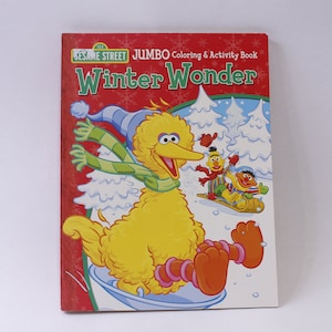 May include: A Sesame Street coloring and activity book titled "Jumbo Winter Wonder". The cover features Big Bird wearing a scarf and hat, sliding down a snowy hill.  Other Sesame Street characters are visible in the background.