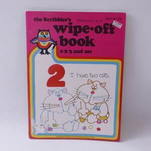 May include: A pink wipe-off book with a colorful owl on the cover. The book is titled "The Scribbler's Wipe-Off Book" and features the number "2" and the text "I have two cats."