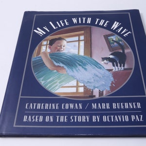 May include: A blue book cover with a picture of a boy holding a large wave in a room with a window and a cat. The title of the book is "My Life With The Wave". The author's names are Catherine Cowan and Mark Buehner. The book is based on a story by Octavio Paz.