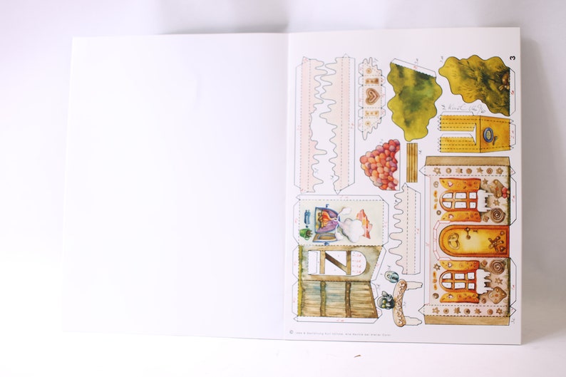 May include: A papercraft model kit featuring a detailed illustration of a whimsical house with a chimney, windows, and a door. The kit includes various pieces to assemble the house, including a roof, walls, and decorative elements. The house is surrounded by a green garden with trees and flowers.