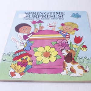 May include: A children's activity book with a colorful cover featuring a pink Easter egg, a yellow chick, a white bunny, a dog, and two children. The book title is "Springtime Surprises! Things to Make and Do."