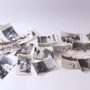 May include: A collection of black and white photographs, some with people, some with landscapes, and some with buildings. The photos are arranged in a random pattern on a white surface.
