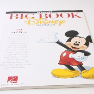 May include: A clarinet music book titled "Big Book of Disney Songs" featuring Mickey Mouse. The cover has the Disney logo in yellow and red text. Mickey Mouse is depicted in his classic outfit. The book lists 72 songs.