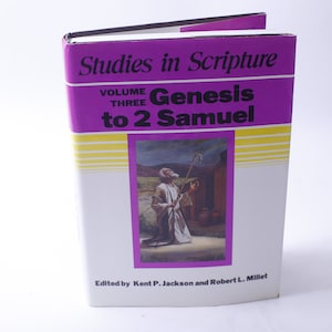 Può includere: Un libro bianco con una copertina viola e strisce gialle. Il titolo è "Studies in Scripture" con il sottotitolo "Volume Three Genesis to 2 Samuel". La copertina del libro presenta un dipinto di un uomo con una tunica inginocchiato con un bastone.