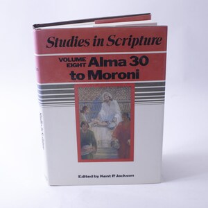 Può includere: Un libro bianco con una copertina rossa intitolato "Studies in Scripture, Volume Eight, Alma 30 to Moroni" con un dipinto di Gesù Cristo e altre tre persone sulla copertina. Edito da Kent P. Jackson.