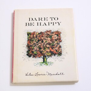 Puede incluir: Un libro vintage titulado "DARE TO BE HAPPY" con una ilustración de un árbol en la portada. El libro tiene una cubierta de color crema con bordes rojos y el nombre del autor, Helen Lourie Marshall, está impreso en la parte inferior.