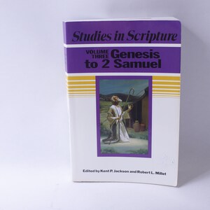 Può includere: Un libro viola e bianco intitolato "Studies in Scripture" con il testo "Volume Three Genesis to 2 Samuel". La copertina presenta un dipinto di un uomo con una tunica bianca che tiene un bastone e guarda il cielo.