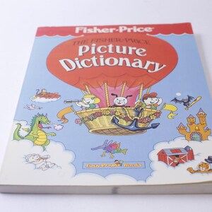 Puede incluir: Una portada de libro colorida con el título "The Fisher-Price Picture Dictionary". La portada presenta un globo aerostático con una cesta llena de flores y un grupo de niños. El libro está publicado por Little People Books.