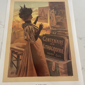 May include: A woman in a long dress and hat looks at a poster advertising the 100th anniversary of lithography at the Galerie Rapp. The poster features a woman in a long dress and a man in a suit. The text on the poster reads "Centenarie de la Lithographie Galerie Rapp".