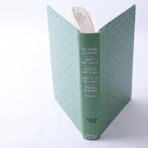 May include: A green hardcover book with the title "The Coming of Arthur" and the author "Tennyson". The book is part of a series called "Everyman's Library".