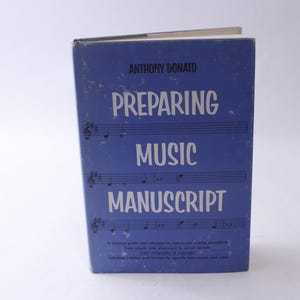 May include: A blue book titled "Preparing Music Manuscript" by Anthony Donato. The cover features musical notation.