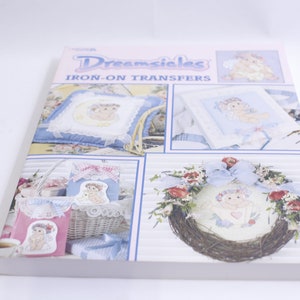 Puede incluir: Un libro titulado "Dreamsicles Iron-On Transfers" que presenta imágenes de varios proyectos de manualidades que utilizan transferencias de planchado. Los proyectos incluyen una almohada, una bolsa de mano, una corona y una bolsa pequeña.