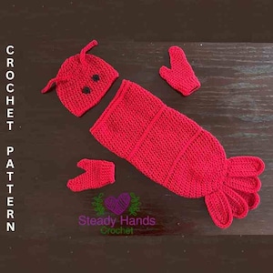 May include: A red crocheted lobster costume for a baby. The costume includes a hat, a body, and two mittens. The costume is made with red yarn and has black eyes.