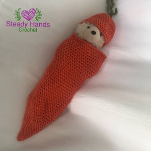 May include: A crocheted carrot-shaped baby blanket and hat set in a bright orange colour. The set is made with a soft, textured yarn and is perfect for a baby shower gift.