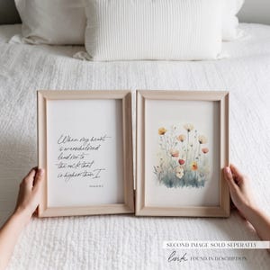 Puede incluir: Dos impresiones enmarcadas, una con una pintura de acuarela de flores silvestres y la otra con una cita manuscrita del Salmo 61:2, "Cuando mi coraz&oacute;n est&aacute; abrumado, gu&iacute;ame a la roca que es m&aacute;s alta que yo."