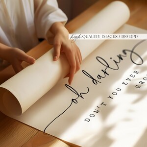 以下が含まれることがあります： 白いポスターに黒い書体で「oh darling don't you ever grow up」と書かれています。ポスターは巻かれており、人の手で持たれています。