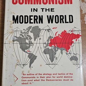 May include: A book cover with the title "Communism in the Modern World" in red and black text. The cover features a world map with the Soviet Union highlighted in red.