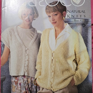 May include: A knitting pattern book titled Proco Natural Knits Book #154. The cover features two individuals wearing textured, button-down knit cardigans in cream and pale yellow, layered over a neutral top and a white collared shirt.