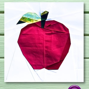 Könnte beinhalten: Ein roter Stoffapfel mit einem grünen Blatt und einem braunen Stiel. Der Apfel befindet sich auf einem weißen Hintergrund.