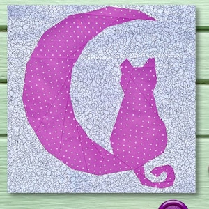 May include: A pink fabric cat silhouette sitting on a pink crescent moon. The fabric has a white polka dot pattern. The background is a white fabric with a black swirl pattern.