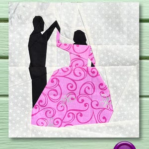 Könnte beinhalten: Ein Papier-Patchwork-Block mit der Silhouette eines tanzenden Paares. Die Frau trägt ein rosa Kleid mit einem wirbelnden Muster. Der Hintergrund ist weiß mit kleinen silbernen Sternen.