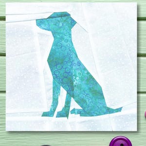 May include: A blue and green fabric dog applique on a white background with a white polka dot pattern. The dog is sitting with its head turned to the left.