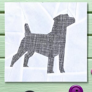 Puede incluir: Un patrón de perro en papel recortado en blanco y negro sobre un fondo blanco. El perro está de pie sobre sus cuatro patas y tiene una cola larga. El patrón está rodeado de un fondo verde claro.