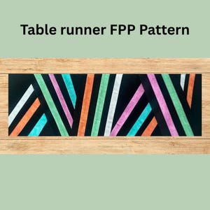 May include: Black table runner with a vibrant geometric design. It features diagonal stripes in white, orange, teal, green, pink, and purple. The text "Table runner FPP Pattern" is at the top.