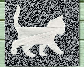 May include: A square fabric quilt block featuring a white cat silhouette appliqued onto a black background. The cat is depicted in profile with a raised tail. The background fabric is covered in a dense, continuous white squiggly line pattern.